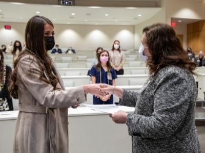 A new initiate shakes hands with her dean